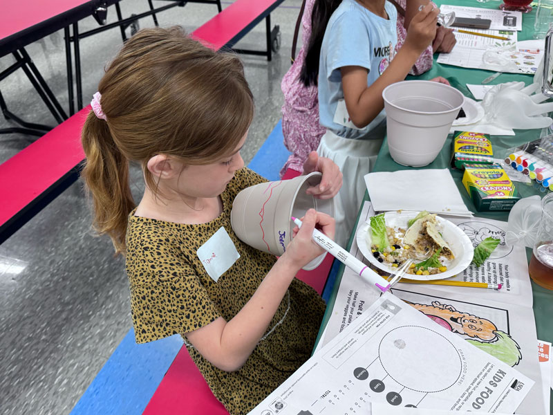 Student writing name on cup