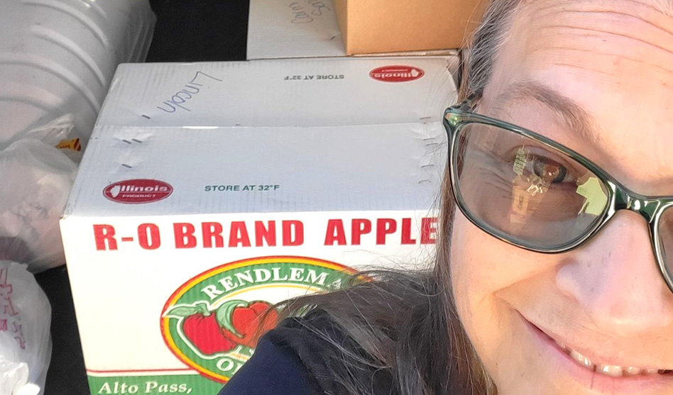 Woman smiling, with box of apples behind her